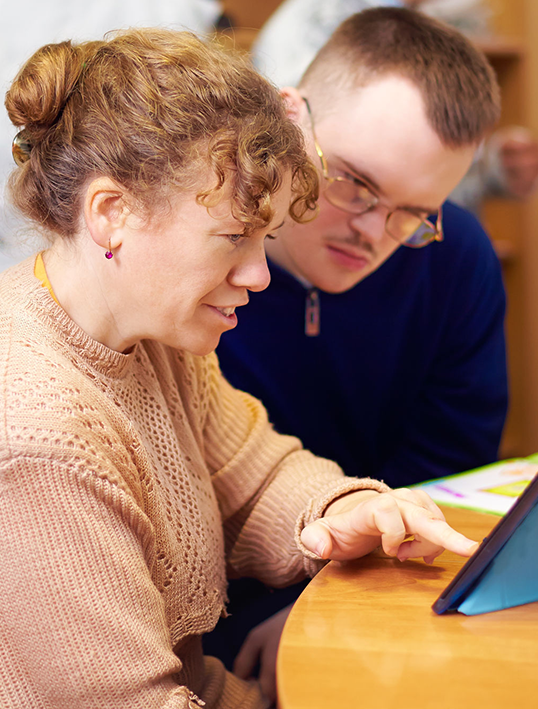 A woman and young man with a disability using a tablet
